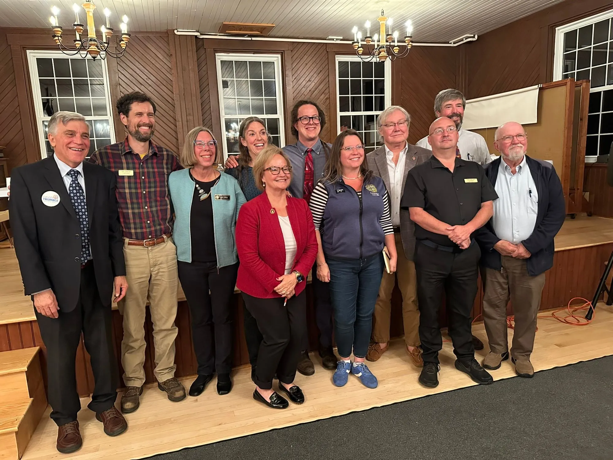 Candidates from both parties standing together on the hall floor for a group photo after the forum